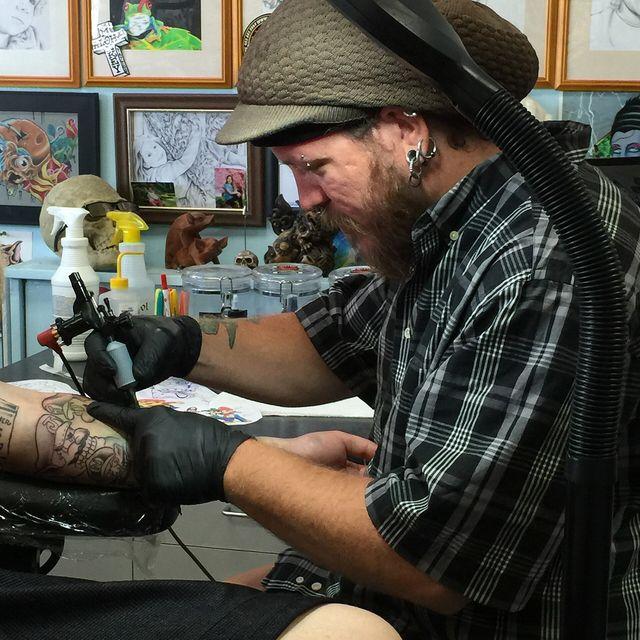 A tattoo artist working on a client's arm